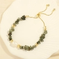 Detailed view of irregular green stone beads with a large white pearl on a gold bolo clasp - Green Rutilated Quartz