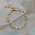Detailed macro view of baroque pearl bracelet on white silk with adjustable gold clasp - Irregular Baroque (Freshwater Pearl) / White