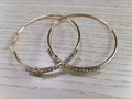 Detail of large gold hoop earrings featuring clear rhinestone accents on wood background - White K Gold