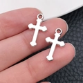 Set di due ciondoli a croce in argento lucido con anellini, tenuti in mano - Croce-11x19mm