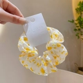 Chouchou en tissu seersucker blanc avec imprimé floral jaune tenu à la main - Chouchou Imprimé Jaune