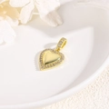 Detalle de un colgante de corazón dorado con circonitas sobre un plato de cerámica - Corazón