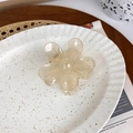 Detail of a translucent champagne flower hair claw clip on a decorative white plate - Light Yellow