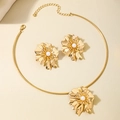 Dettaglio di set collana e orecchini a fiore dorato con perle e petali in metallo - Oro