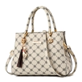 Borsa a mano beige con motivi a quadrifoglio neri, finiture dorate e ciondolo a nappa - Stile Beige (Stampa Beige)