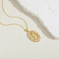 Macro view of gold oval pendant with mother of pearl and saint relief on stone background - Sunburst Virgin Mary