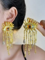 Close-up of gold evil eye tassel earrings with white rhinestones on model's ear - Gold Evil Eye Tassel Earrings
