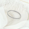 Detail shot of silver bangle with pavé zircons on white feather and silk backdrop - Silver