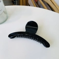 Close-up of a medium-sized glossy black curved hair claw clip on a white surface - Glossy Black