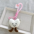 Dettaglio del ciondolo a cuore in peluche con moschettone rosa ed etichetta Current - Cuore bianco con moschettone rosa