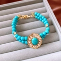 Dettaglio del bracciale con perline turchesi e chiusura floreale dorata con strass - Bracciale (Oro-Blu)
