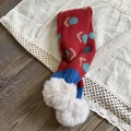 Detail of red knit kids scarf featuring blue tulips and beige faux fur pom-poms on wood - Red