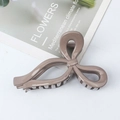 Glossy coffee brown bow-shaped hair claw clip on magazine background - Milk Tea Coffee