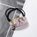 Detail of square acetate hair tie with colorful marble patterns and gold metal trim - Colorful