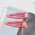 Detail of two pink metal drip hair clips with white decorative elements on paper - Watermelon red
