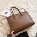 Grande borsa tote marrone esposta su tessuto morbido con un design estetico minimalista - Marrone