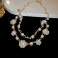 Primer plano de collar dorado de doble capa con perlas blancas y colgantes de pedrería - Collar de Perlas y Diamantes de Imitación de Doble Capa - Dorado