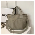 Detail of khaki nylon tote bag showing the front pocket with metal snap and wide strap - Light Green