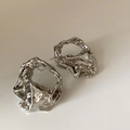 Macro detail of silver U-shaped earrings featuring a molten texture and mirror finish - Silver