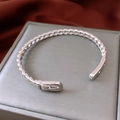 Macro detail of silver belt-buckle style open bangle resting on a gray jewelry box - Silver
