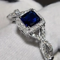 Close-up of a blue square sapphire ring with a halo of white diamonds and twisted silver band - US 5 / Blue