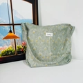 Detail of green floral canvas tote bag showing peacock feather pattern and stitched label - Peacock Feathers