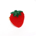 Detail of red strawberry resin ring with green leaves and a golden metal band - Strawberry