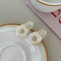 Gros plan de barrettes à fleurs en acétate crème avec texture marbrée sur assiette - Blanc glacé