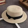 Detail of beige straw boater hat with a black ribbon bow on a gray textured rug - M (56-58cm) / Beige