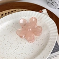 Detailed view of a pink translucent flower hair claw clip on a white ceramic plate - Lotus root pink
