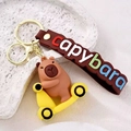 Porte-clés capybara marron sur scooter jaune avec lanière en cuir et crochet doré - Planche à Roulettes