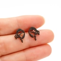 Detailed view of matte black minimalist hollow line girl face earrings on fingers - Black