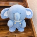 Lichtblauwe pluche olifant met gestreepte corduroy tuinbroek op een houten trap - Olifant in Blauwe Tuinbroek / Blauw Hemd Stijl