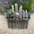 Detailed view of raw blue crystals and silver sun pendant on a black metal hair comb - Blue Kyanite Black Wire Silver Sun