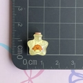 Primer plano de un dije de botella de deseos con forma de estrella sobre una regla - Botella Estrella Amarilla
