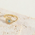 Close-up of golden Evil Eye ring with micro-pave crystals and a white pearl detail - Pearl Evil Eye