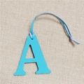 Close-up of blue lychee texture leather letter A charm with rope on linen backdrop - Letter A Sky Blue