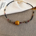 Detailaufnahme der Acryl-Keramikperlenkette mit Tigerauge-Stein und ethnischen Motiven - Gold Schwarz Kaffee