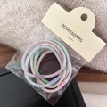 Close-up of colorful high-elastic hair ties in clear packaging on a beige sweater - Plain Smooth Style