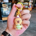 Brown silicone Capybara keychain with purple hat and green striped ball in hand - Light-up Tennis Capybara - Yellow