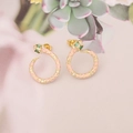 Detailed close-up of golden snake stud earrings with pink enamel and green gemstone eyes - Pink