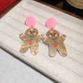 Close-up of festive Christmas gingerbread man earrings with pink studs and green bow details - Gingerbread Man Style