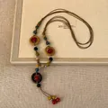 Detailopname van de etnische leren ketting met kleurrijke harskralen en houten ringen - Multicolor Ring (HN8655)