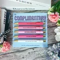 Close-up of complimentary pen set with gold clips and motivational quotes on wooden desk - Complimentary Theme