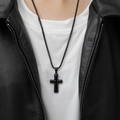 Primer plano de un collar con colgante de cruz de acero de titanio negro con chaqueta de cuero - Colgante único negro (sin cadena)