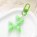 Close-up of holographic neon green balloon dog keychain with green metal hook on a tray - Green