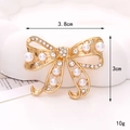Detail view of a 3.8cm gold bow brooch with white pearls and sparkling rhinestones - D2474 38mm*30mm Gold Ribbon Pearl Bowknot