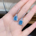 Nahaufnahme von rechteckigen blauen Edelsteinohrringen mit glitzerndem Halo-Effekt - 925er Silber / Blaue Zirkonia (ED138)