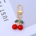 Detailed view of sweet red cherry keychain with gold hook and green enamel leaves - Style A-Solid Red Cherry