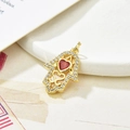 Macro shot of gold Hamsa hand pendant with red heart gemstone and clear zircon accents - Dark Red Zirconia
